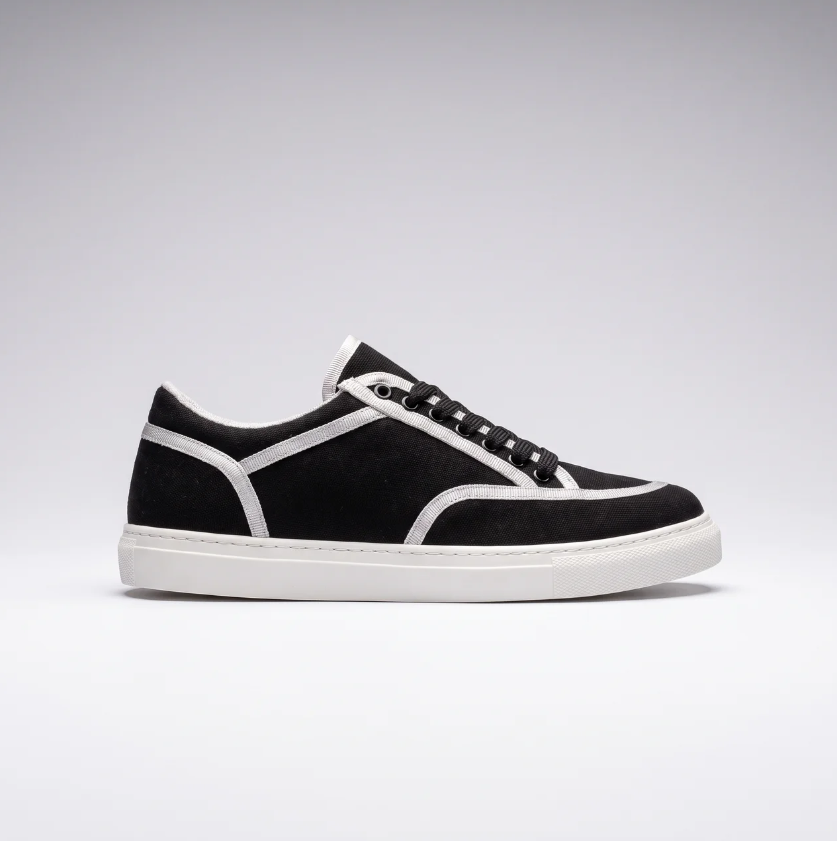 Black Vans sneakers by Shopify featuring classic low-top design and white rubber soles.