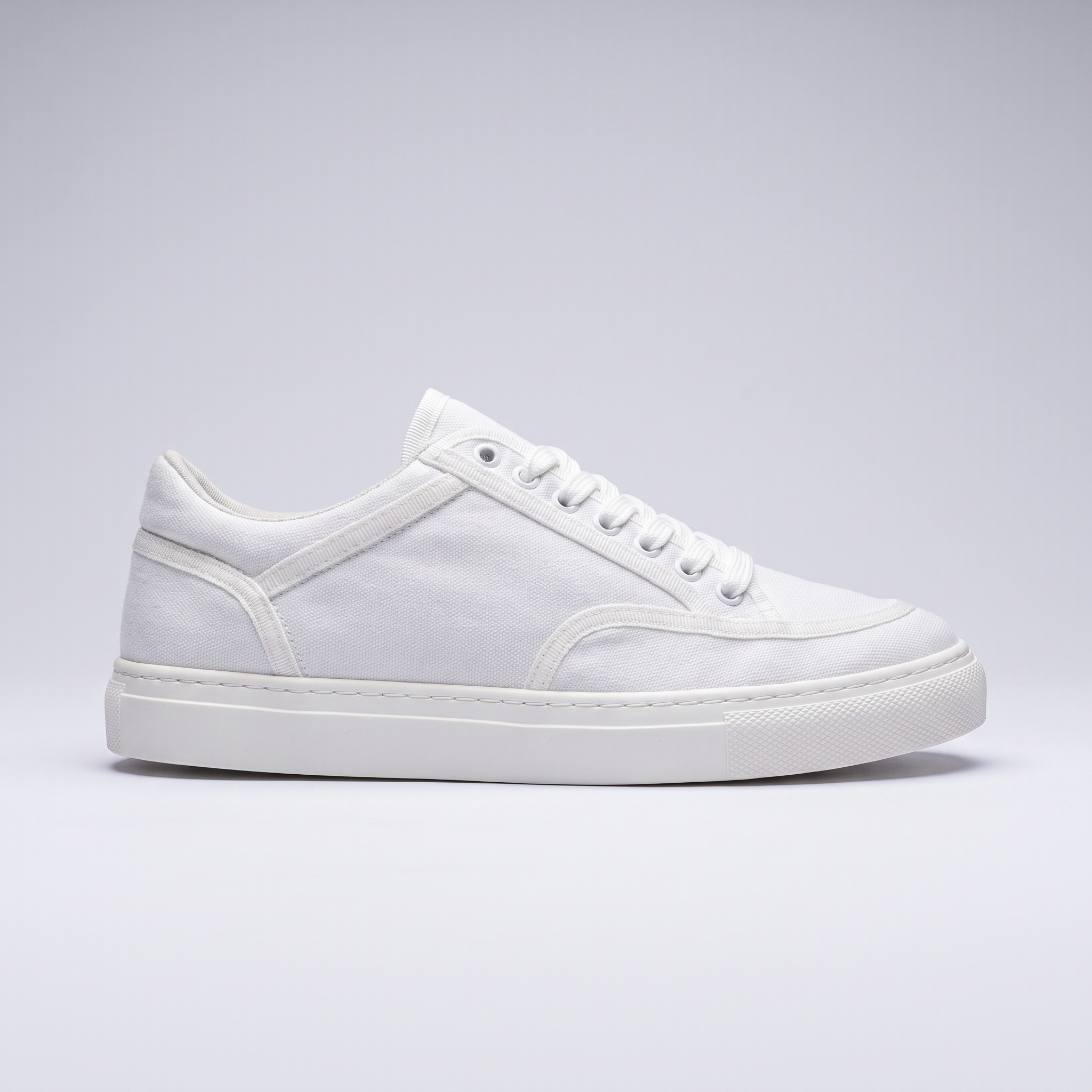 White VAN sneakers by Shopify featuring a sleek design, white laces, and a comfortable rubber sole.