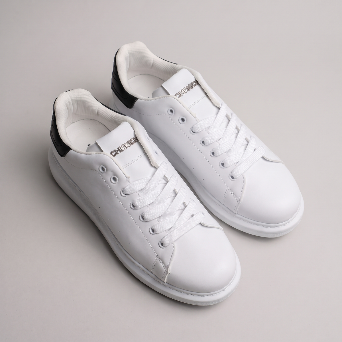 Black ORIGIN sneakers by Shopify with sleek design, white soles, and breathable fabric, shown from a side angle.