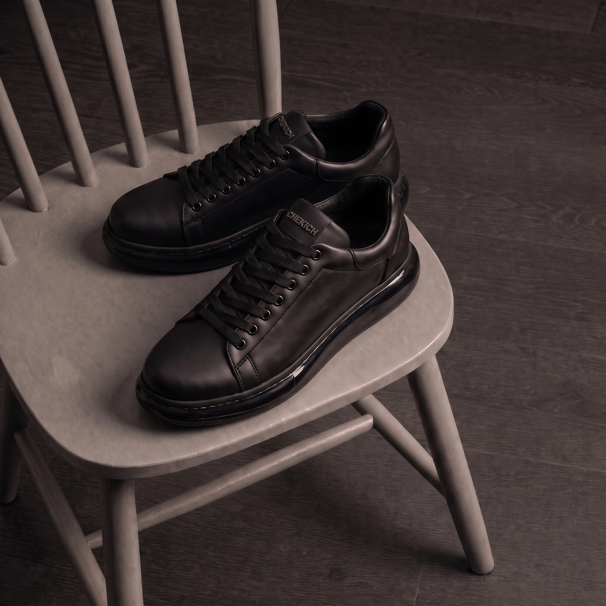 Chekich FANTASIA X All Black sneakers pair displayed on a wooden chair