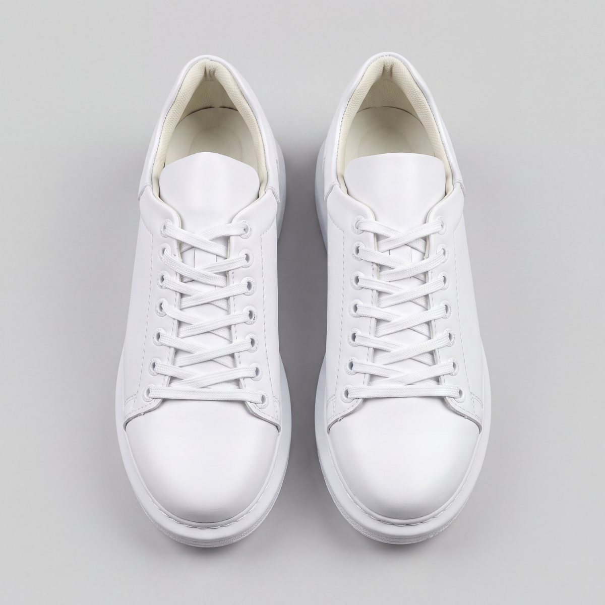 White Shopify Fantasia Plain sneakers with smooth leather upper and white laces, shown from a side view.